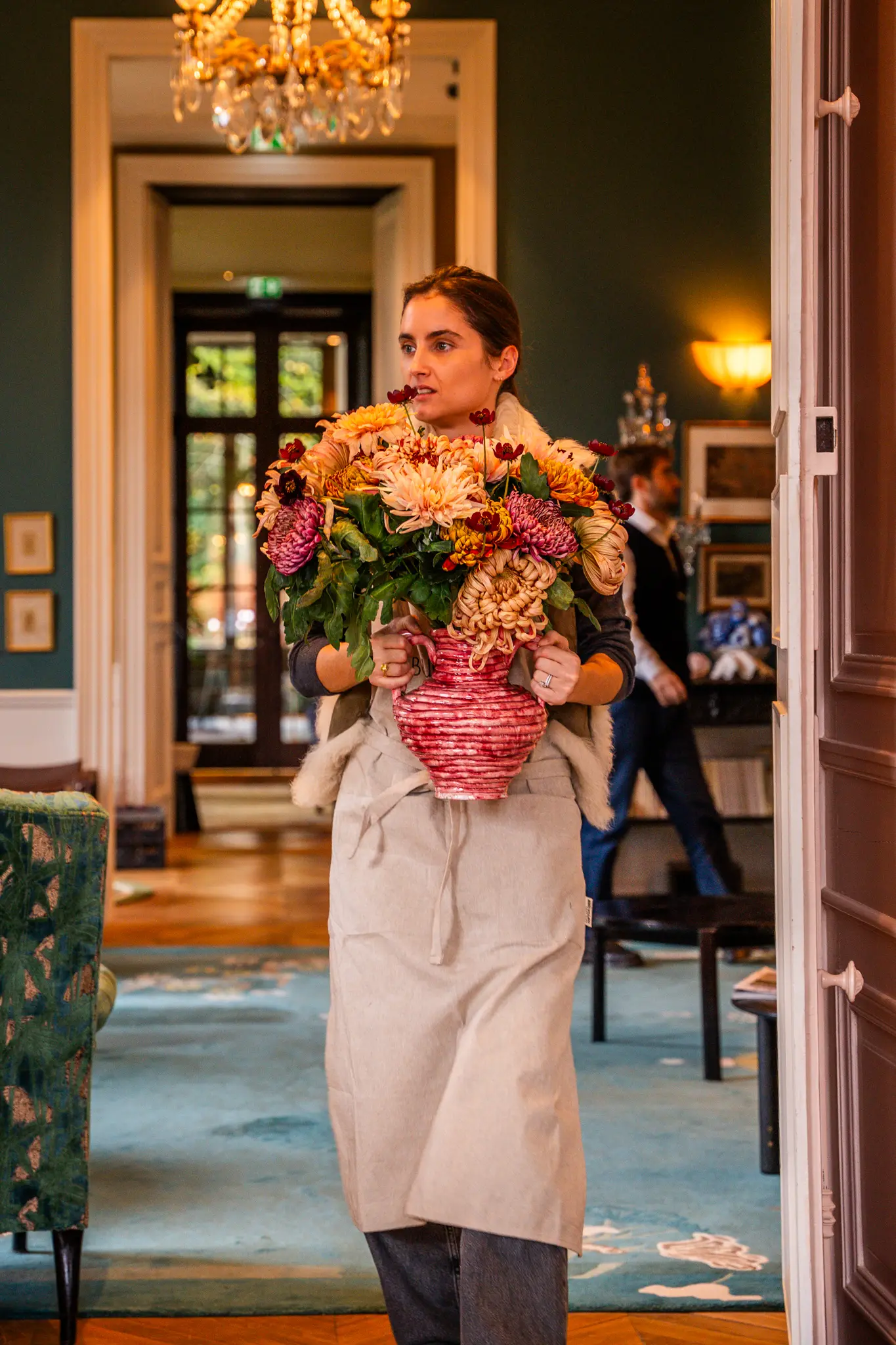 Reportage photo en entreprise : une fleuriste porte une composition florale dans les bras Reportage photo en entreprise : une fleuriste porte une composition florale dans les bras