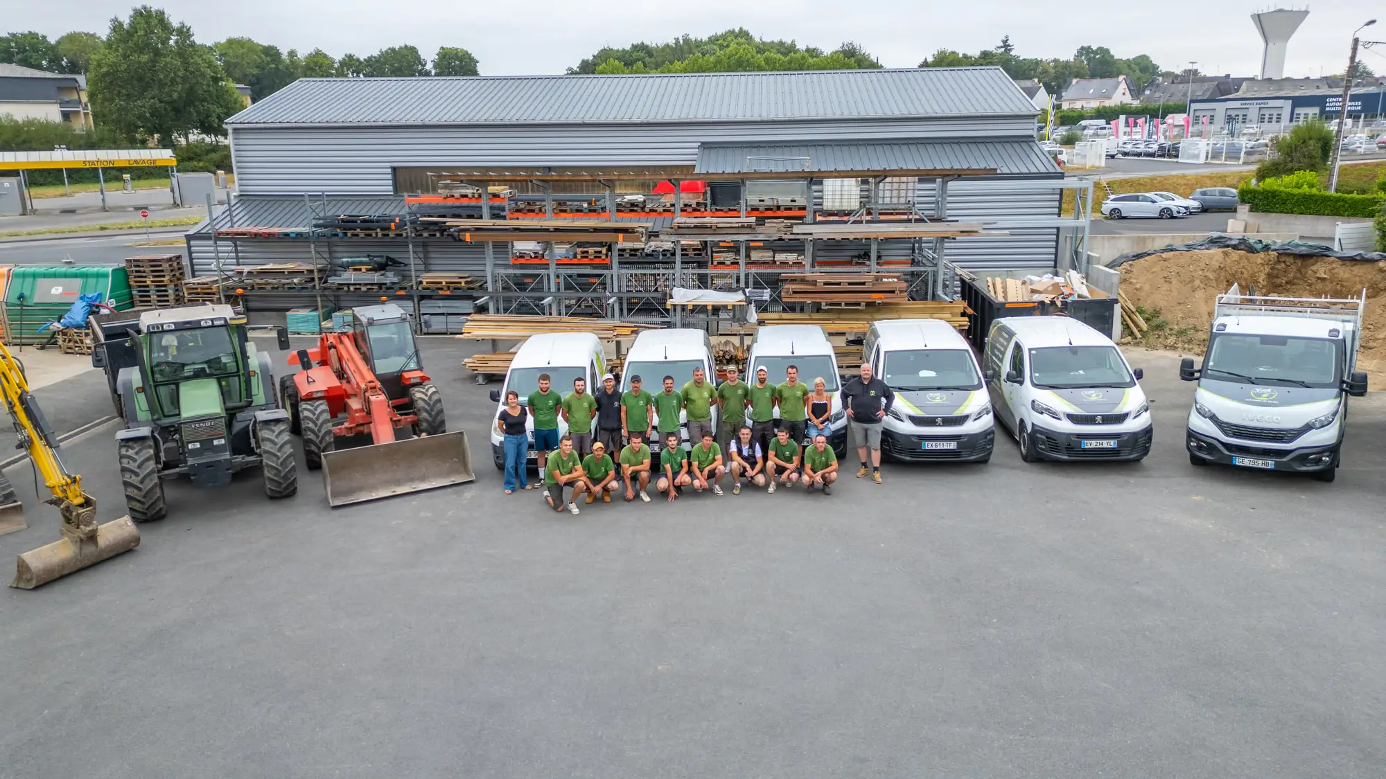 Vue aérienne d’une équipe d’entreprise rassemblée devant sa flotte de véhicules, en Bretagne