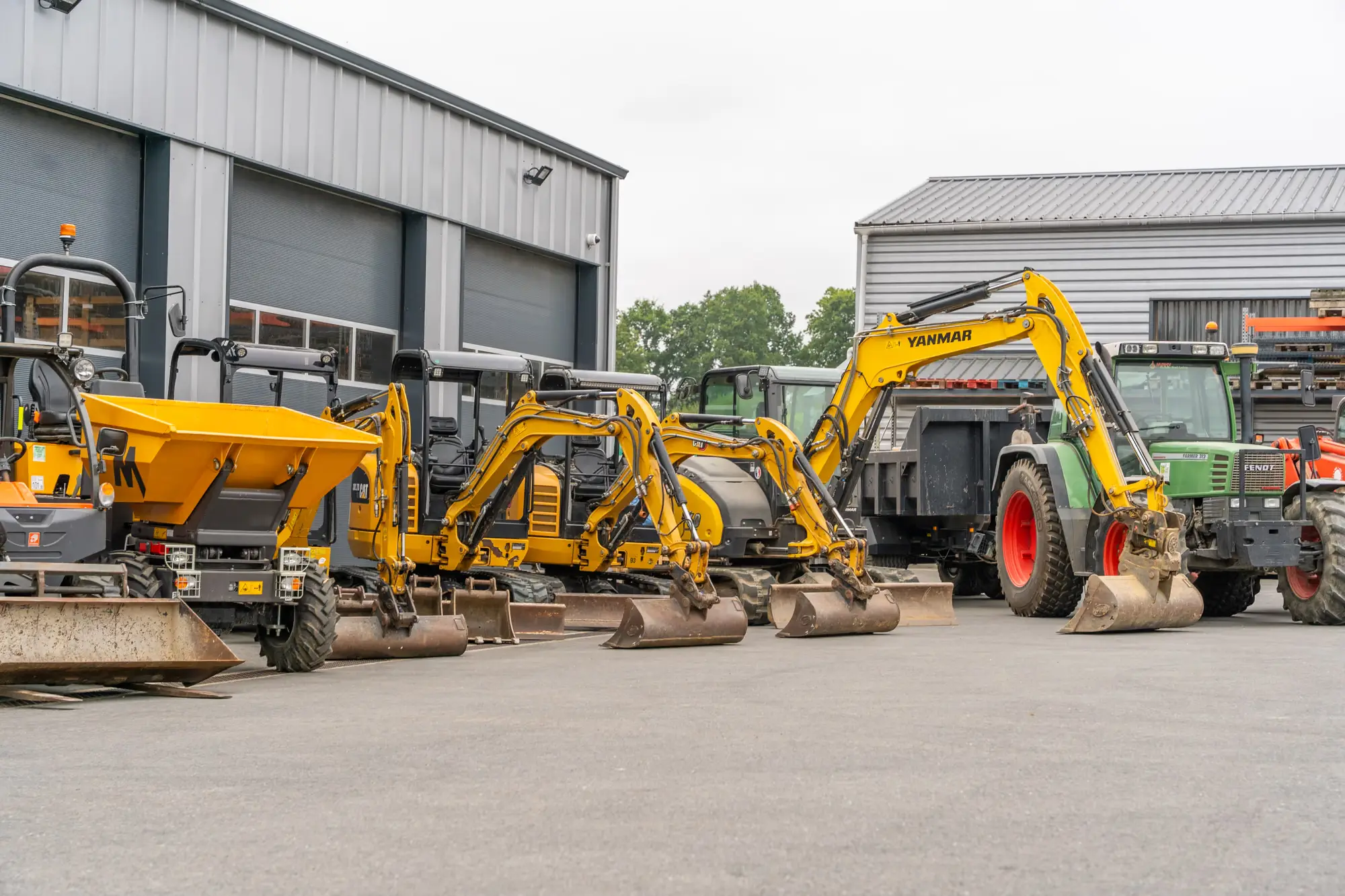 Minipelles et dumper alignés devant le hangar d’une entreprise de paysage, à Loudéac
